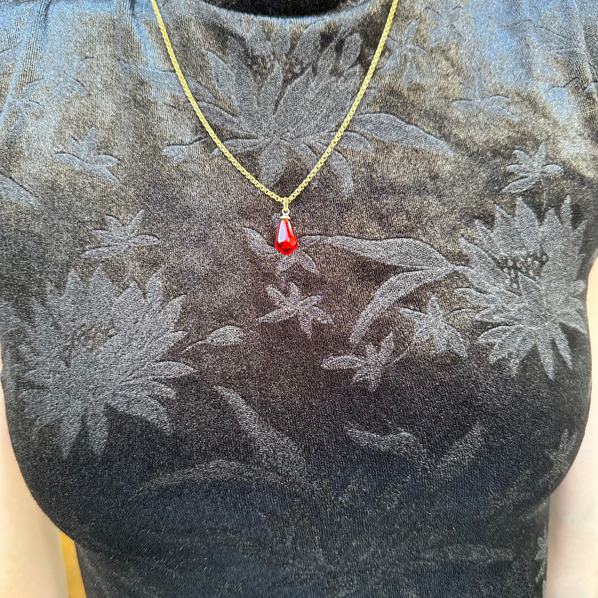 pomegranate seed necklace with gold-plated stainless steel chain, modeled a woman wearing a black velvet dress.  view from the front