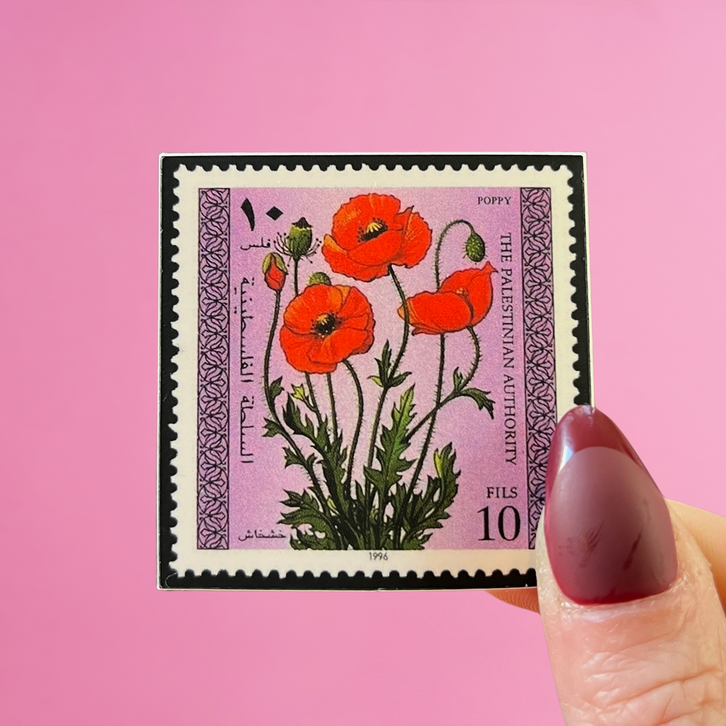 Front view of fingers holding a Palestine stamp with an image of a poppy flower. Against a pink background