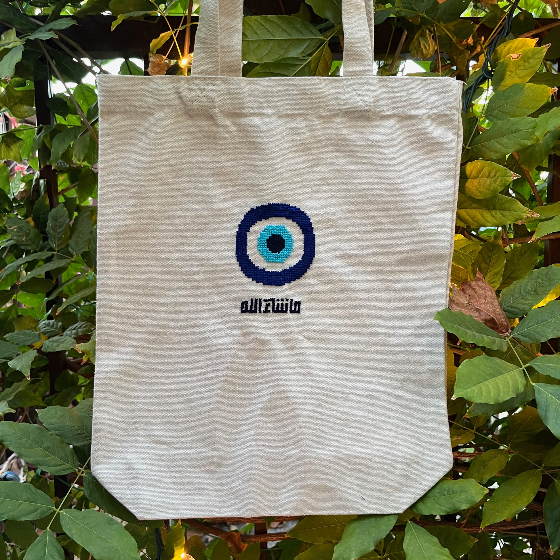 Finished tatreez tote bag kit with evil eye design. beige tote bag, view from the front