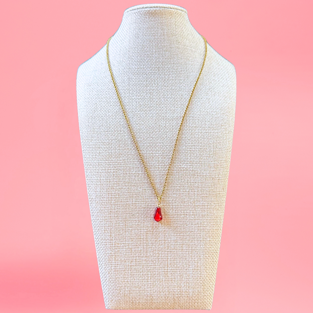 pomegranate seed necklace modeled on beige bust with pink background. with gold-plated stainless steel chain. view from the front