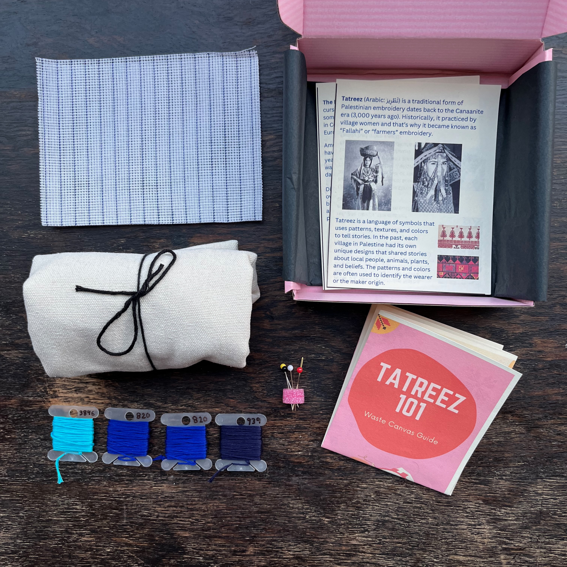 Tatreez tote bag kit with evil eye and mashallah pattern, beige tote bag, pink Rahaal tatreez kit box, embroidery threads, DMC embroidery needle and sewing pins and tatreez instructions for beginners. view from above