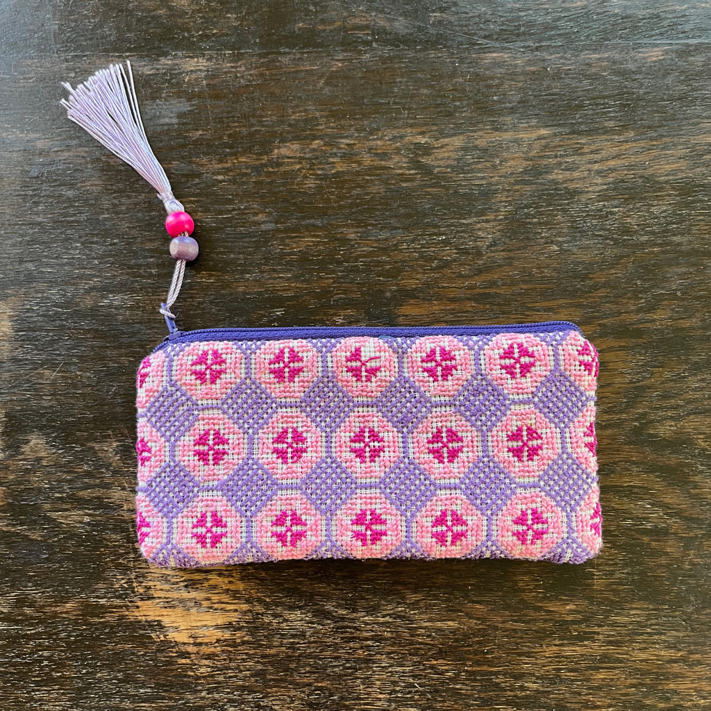 Palestinian tatreez embroidered purse/wallet/clutch bag. red, pink, and purple star moon design. lying on a wooden table. view from above