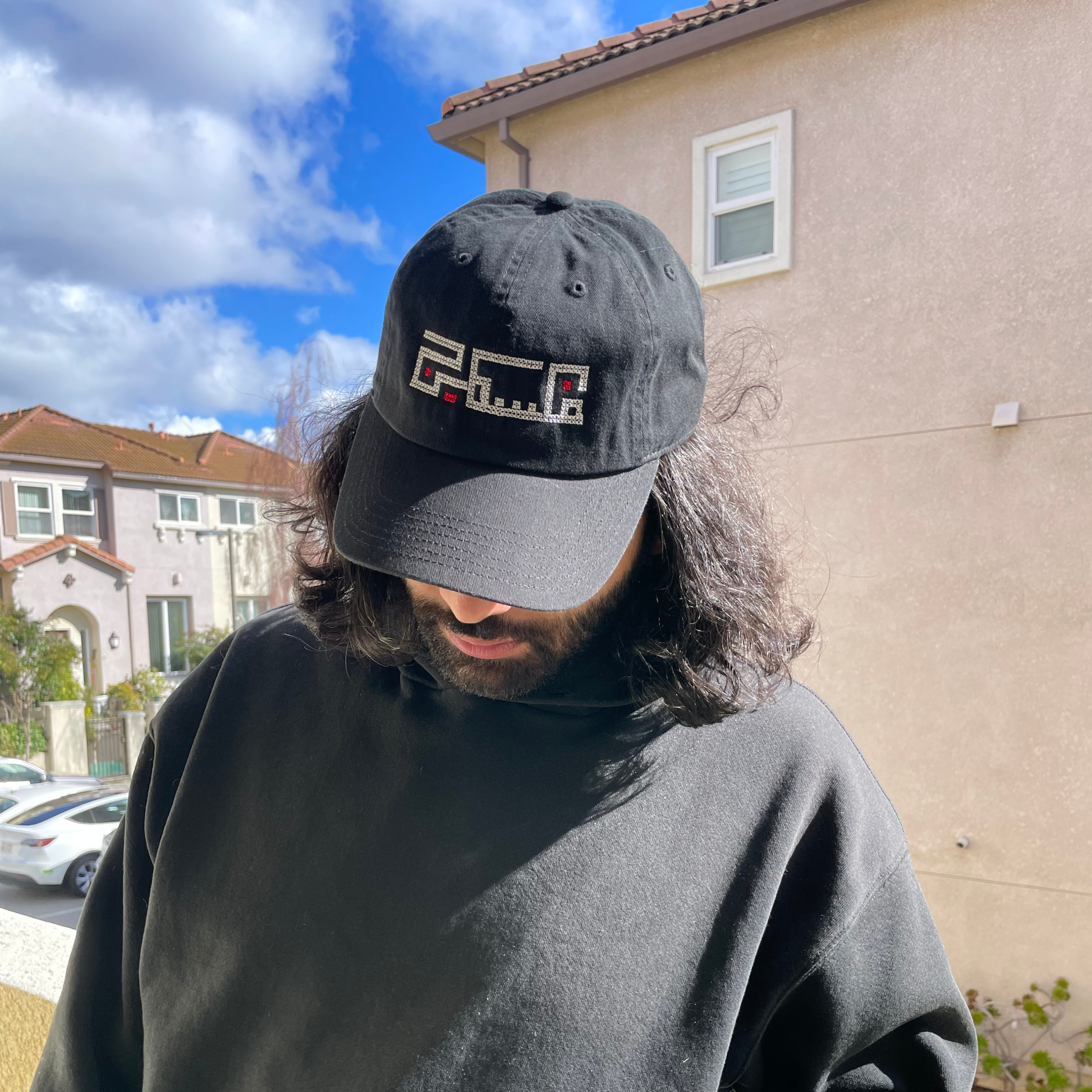 Palestinian embroidered black baseball hat, adjustable and made from 100% Cotton. This hat features an original embroidered design of the word "Palestine" using Arabic Kufic calligraphy. modeled on palestinian man. view from the front