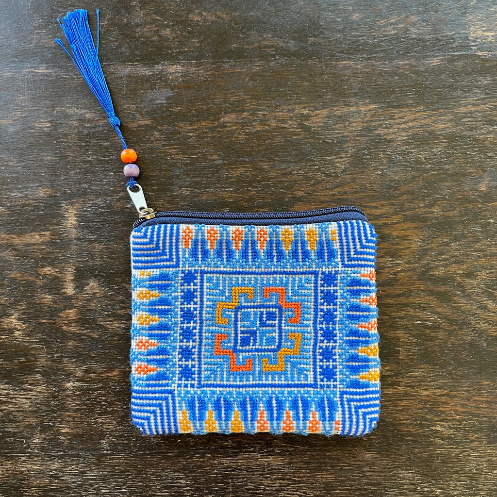 Palestinian tatreez embroidered purse/wallet/clutch bag. blue and orange cypress tree and moon with feathers design. lying on a wooden table view from above