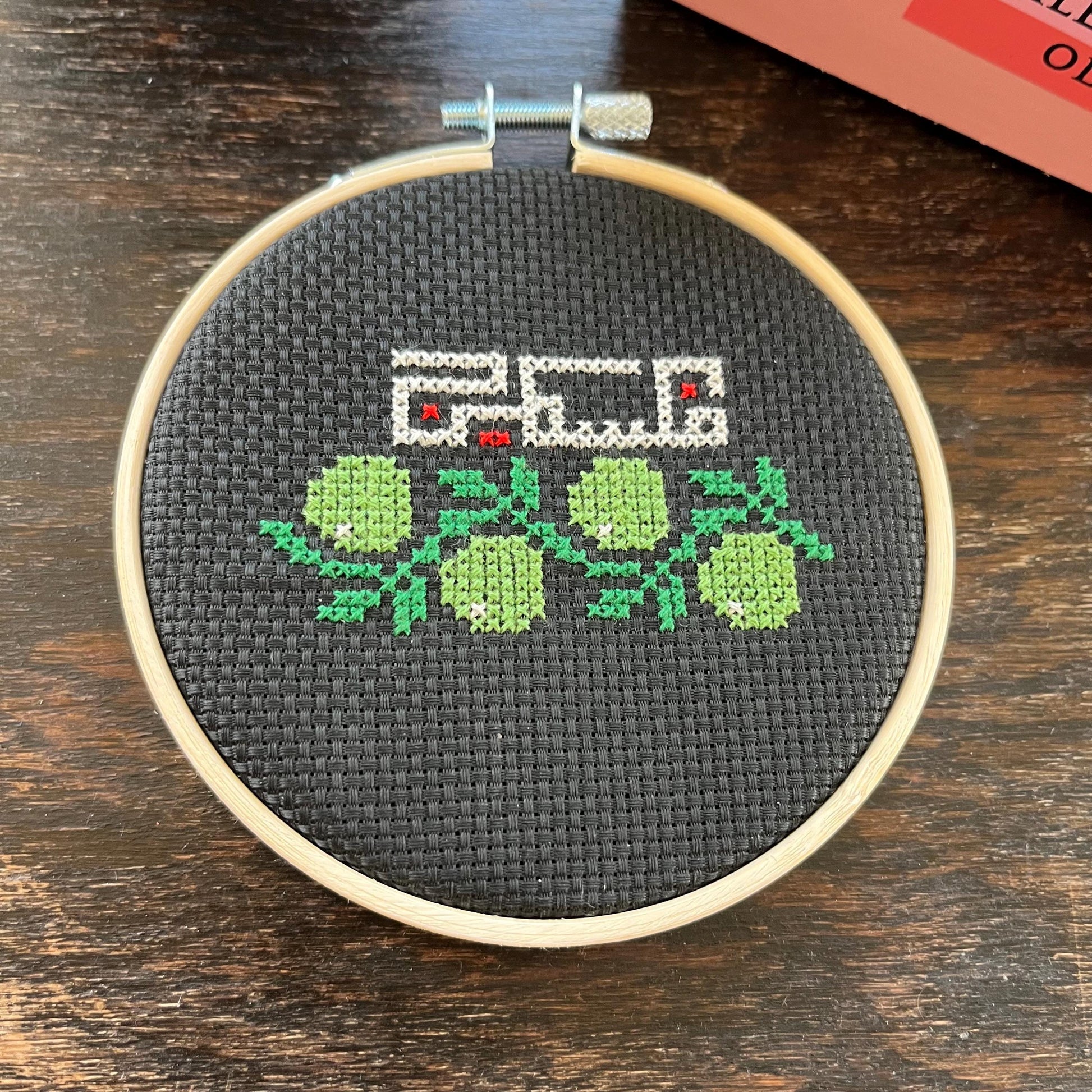 Tatreez kit with olive branch and Palestine design. black aida cloth in embroidery hoop. view from above