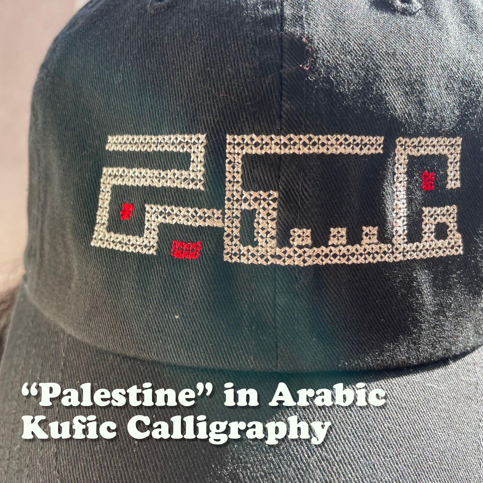 close-up of embroidered black baseball hat, with an original embroidered design of the word "Palestine" using Arabic Kufic calligraphy. view from the front