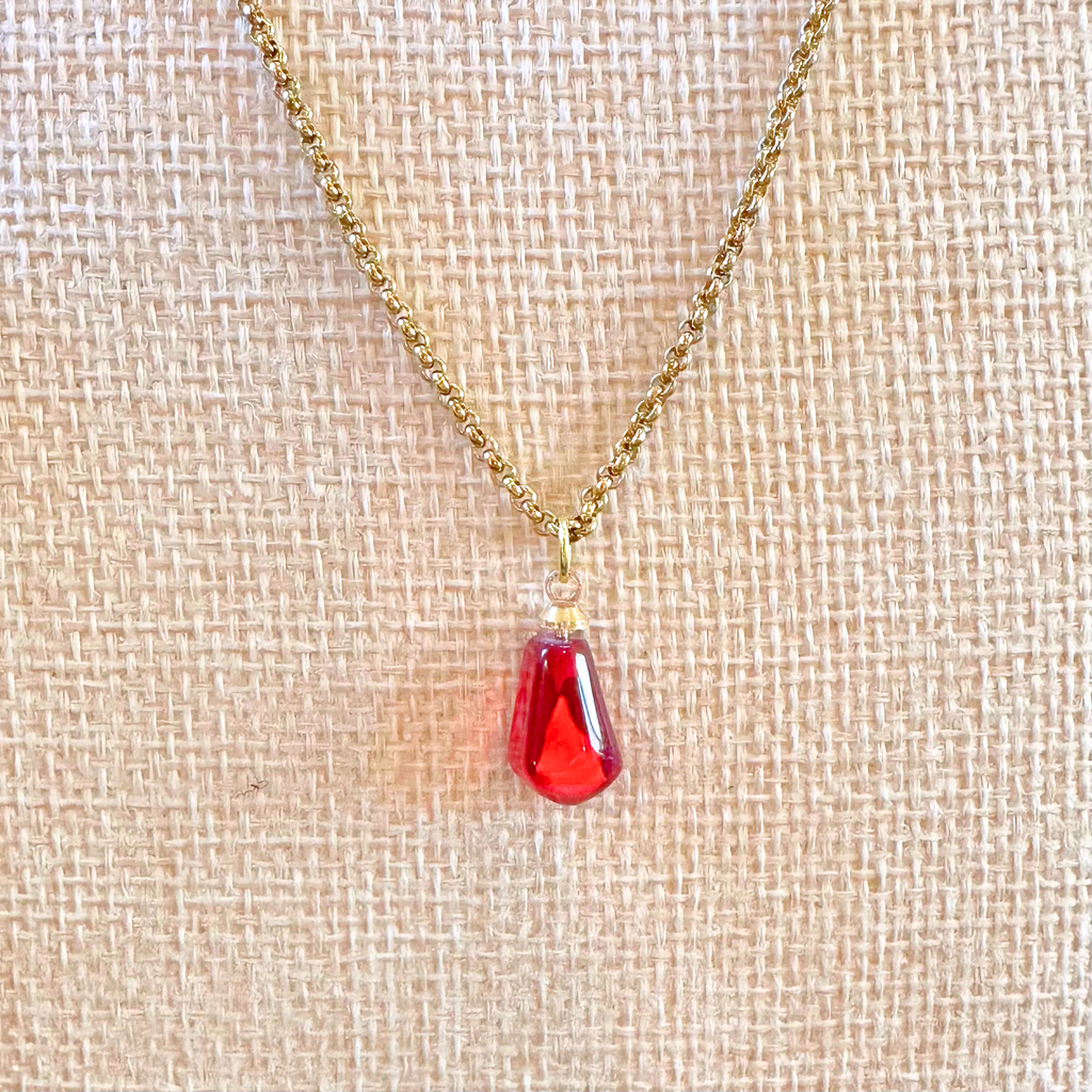 close-up of pomegranate seed necklace modeled on beige bust. with gold-plated stainless steel chain. view from the front