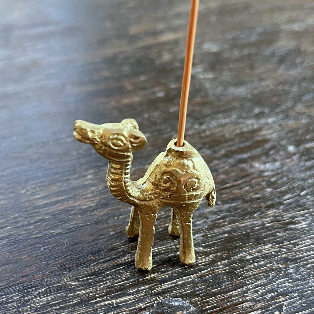 brass, gold camel incense holder, side view standing on a wood table