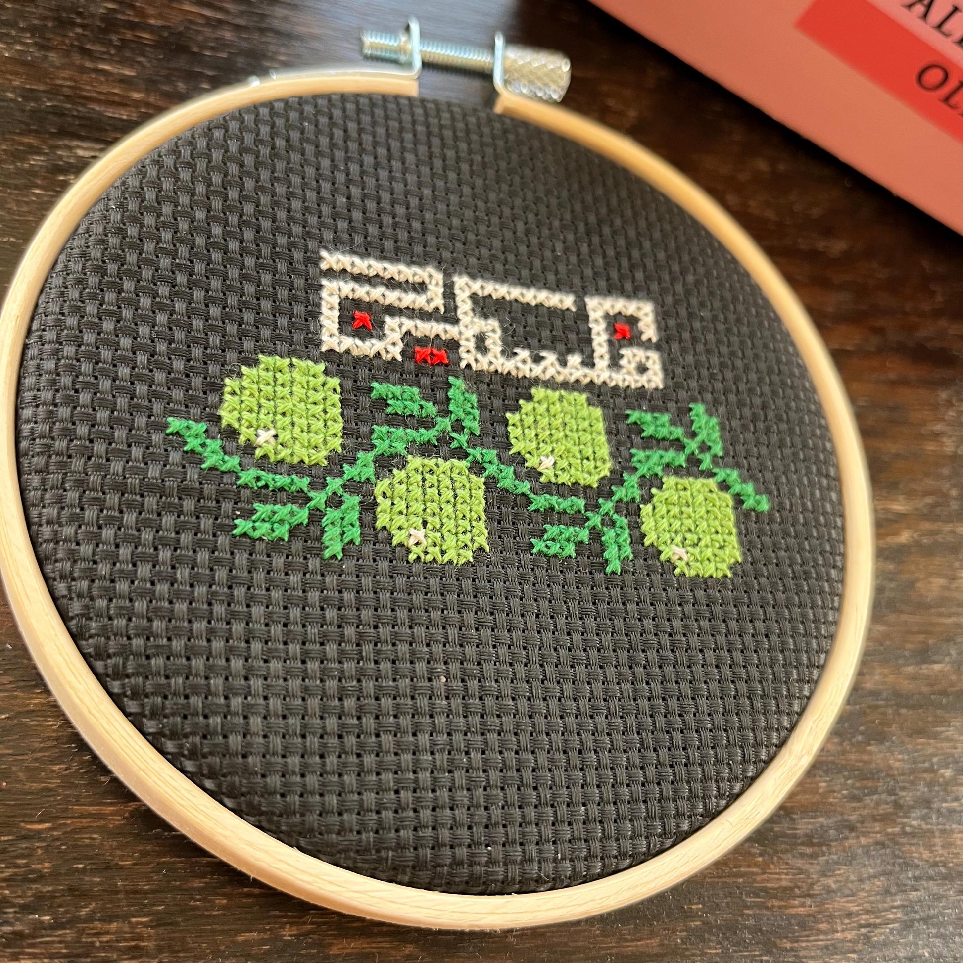 Tatreez kit with olive branch and Palestine design. black aida cloth in embroidery hoop. view from above