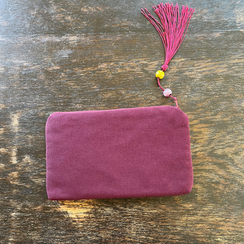 Palestinian tatreez embroidered purse/wallet/clutch bag. red and purple moon with feathers design. lying on a wooden table, view of the bacside from above