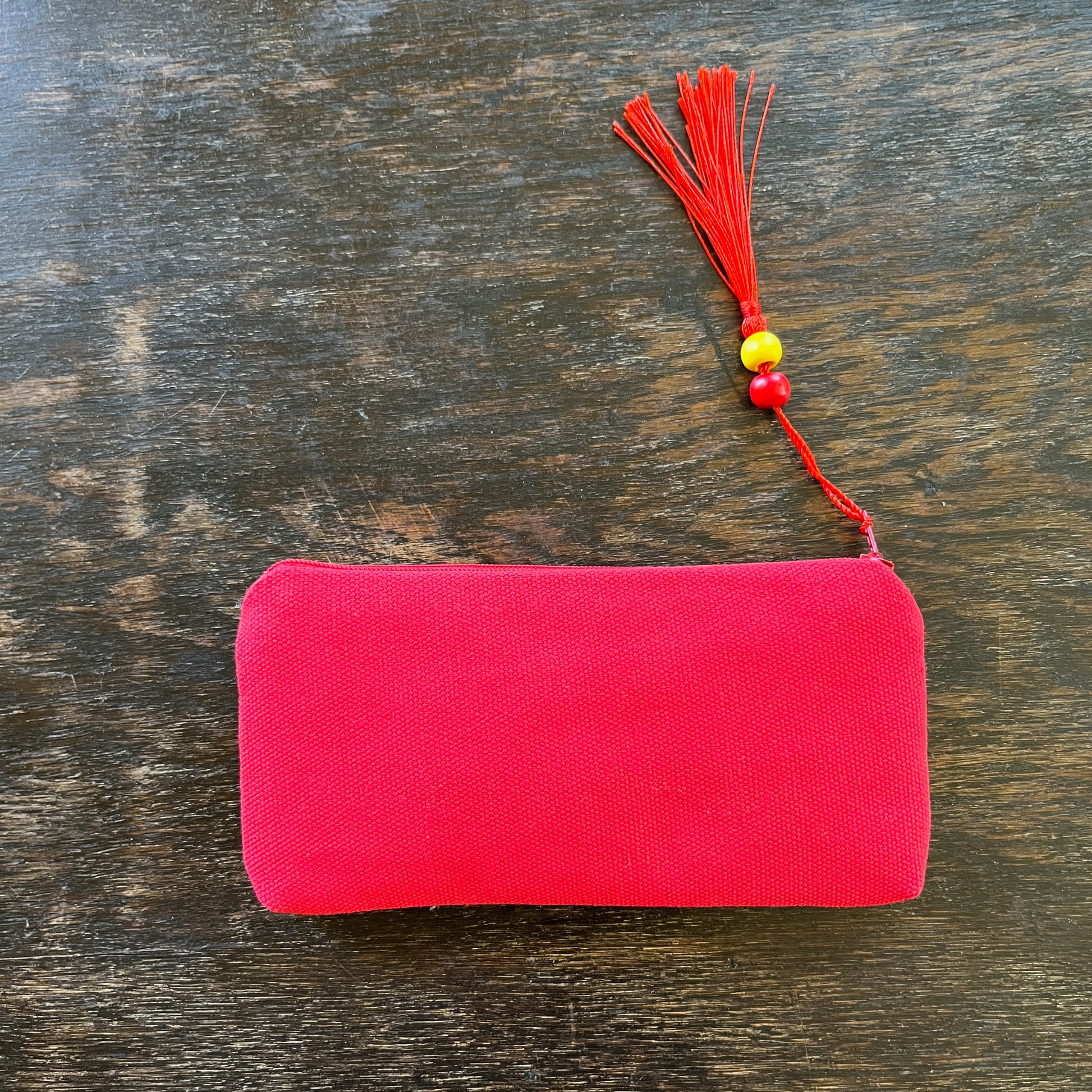 Palestinian tatreez embroidered purse/wallet/clutch bag. red, yellow, and purple star moon design. lying on a wooden table. view of backside from above