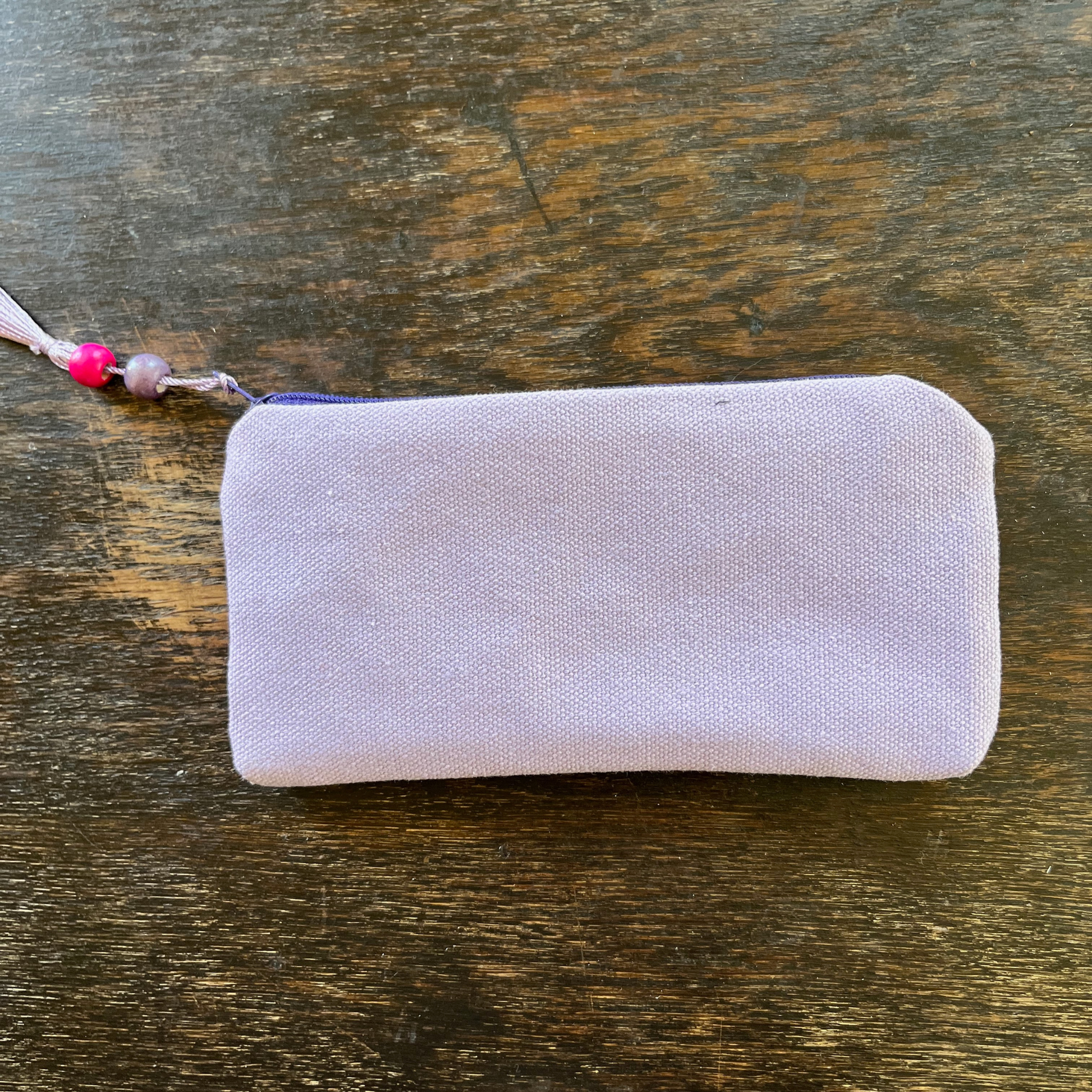 Palestinian tatreez embroidered purse/wallet/clutch bag. red, pink, and purple star moon design. lying on a wooden table. view of backside from above