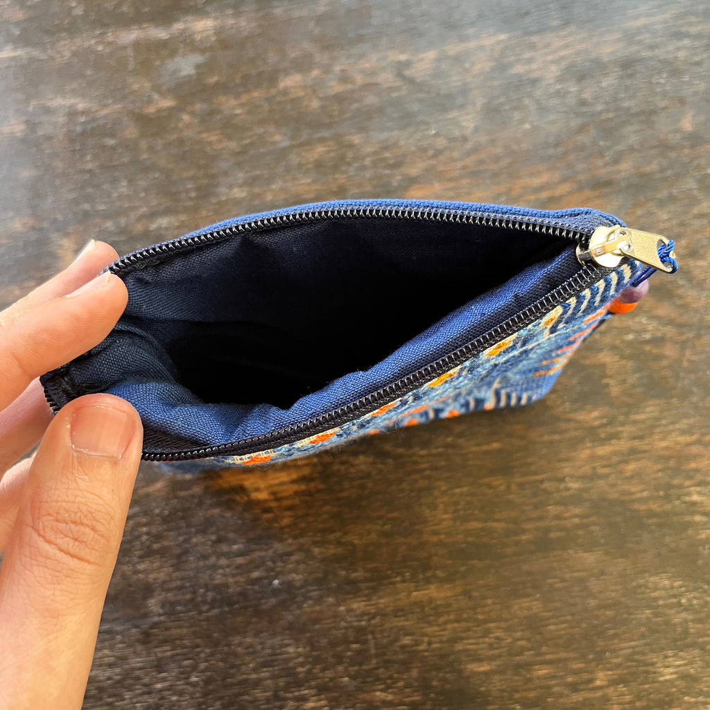 Palestinian tatreez embroidered purse/wallet/clutch bag. blue and orange cypress tree and moon with feathers design. unzipped on a wooden table view of inside from above