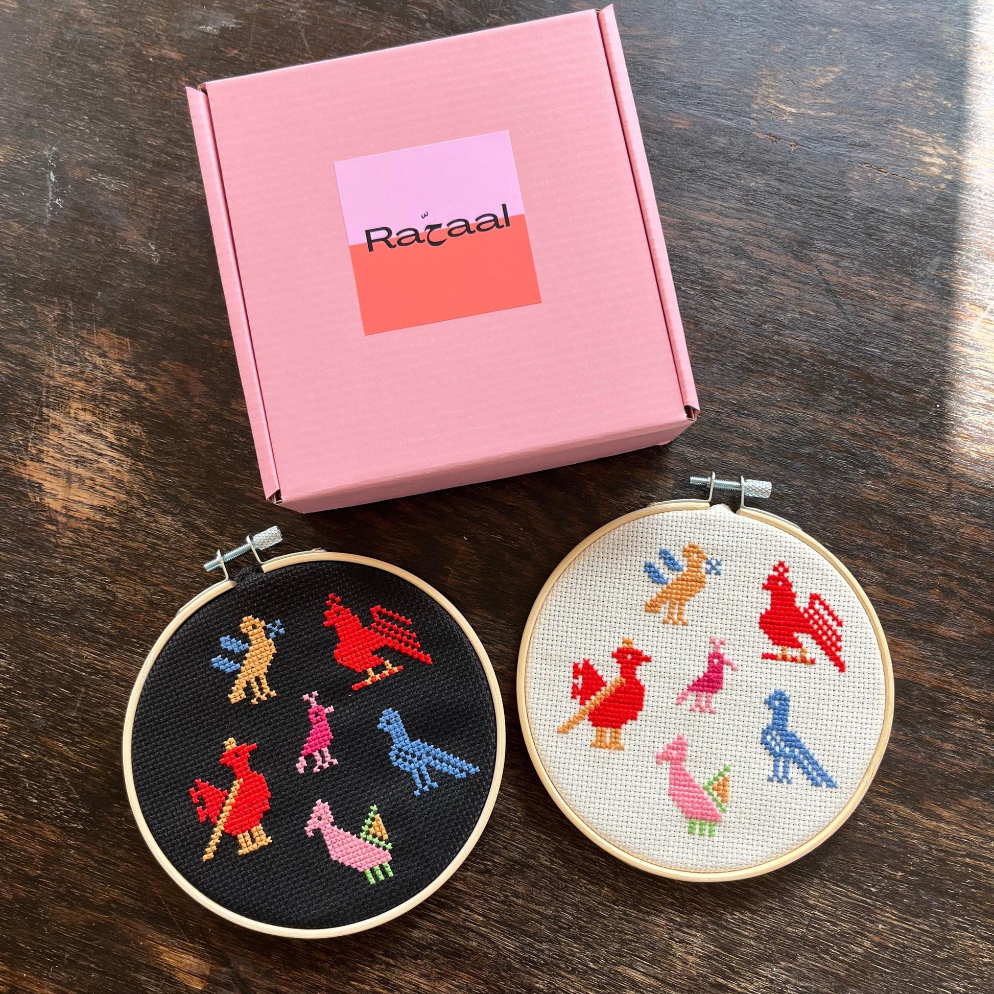 Tatreez kit with birds of Ramallah dedsign. black and white aida cloth, embroidery hoops, pink Rahaal tatreez kit box, view from above