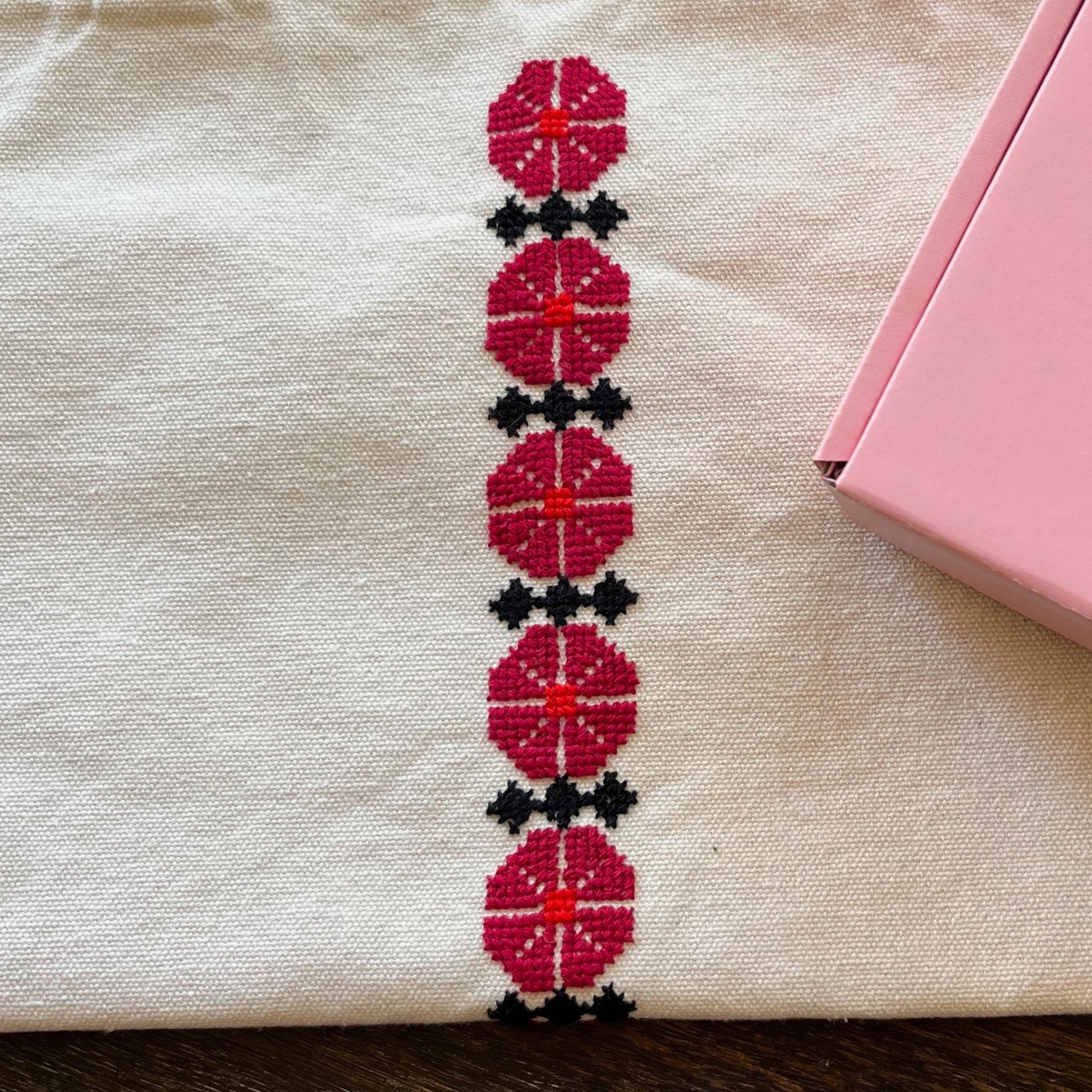 Close up of Ramallah flower tatreez design on beige tote bag. view from above